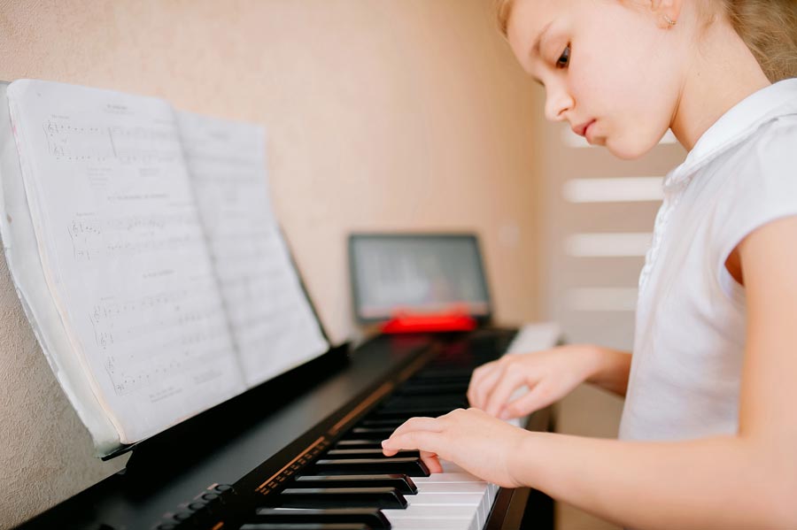 Petite fille suivant des cours de piano en ligne