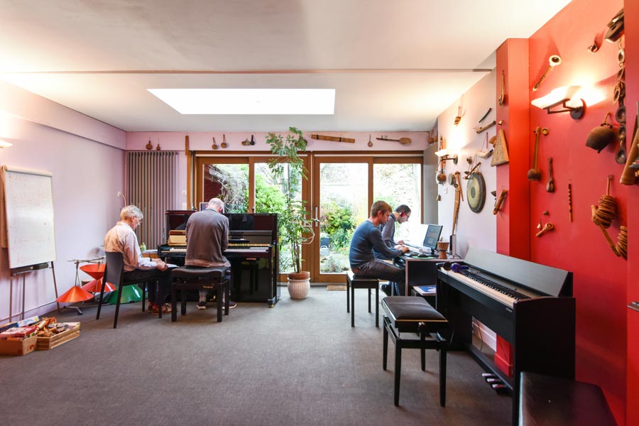 Salle des cours de l'école Régis Bonneel avec plusieurs personnes s'entraînant au piano