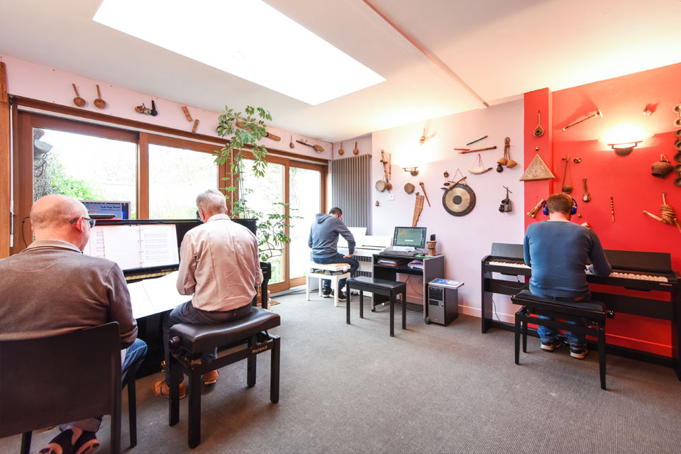 Groupe de personnes apprenant ensembles à jouer du piano