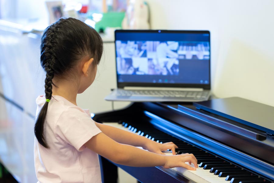 Petite fille jouant du piano en assistant à un cours en ligne