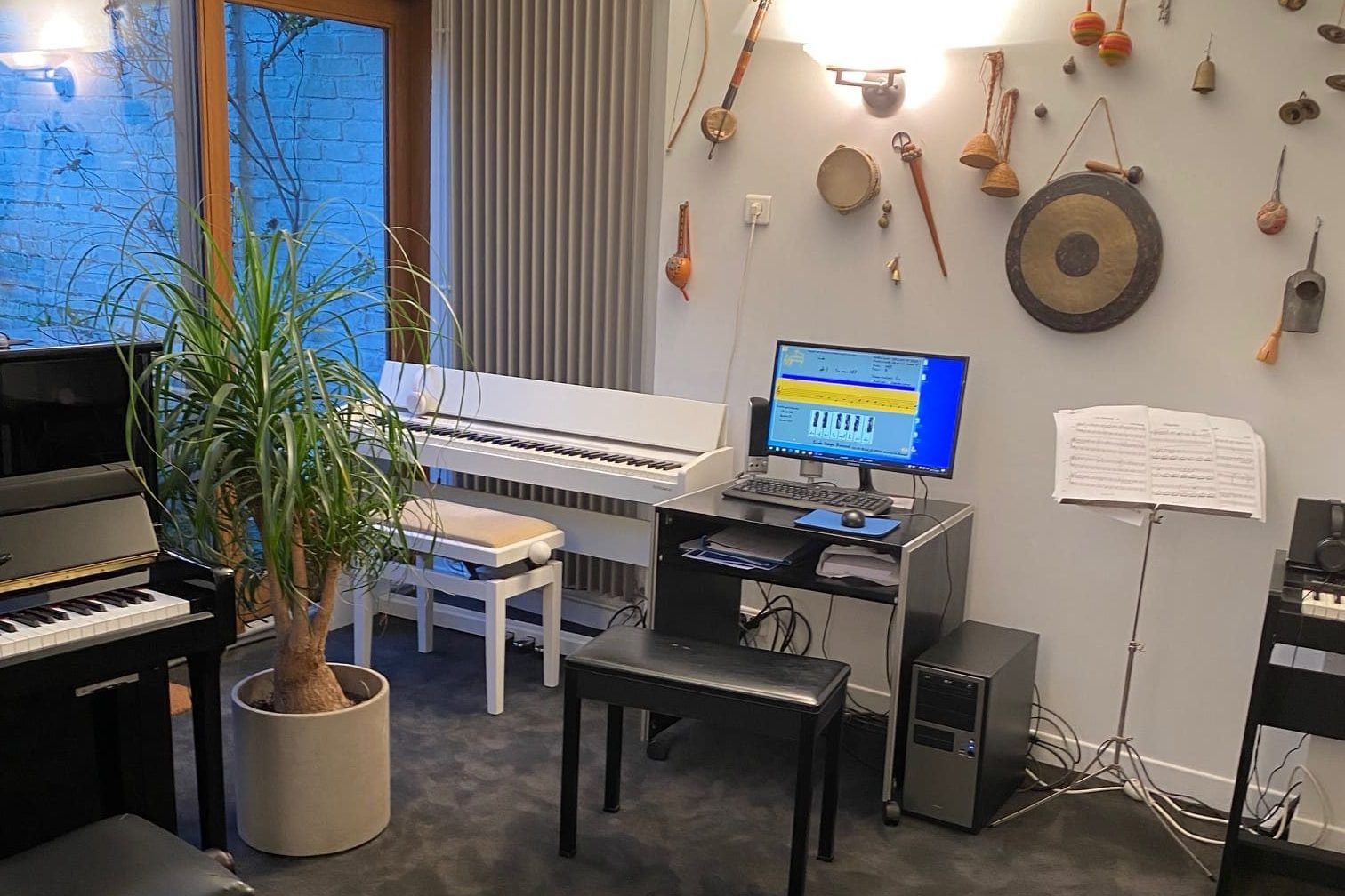 Salle avec 3 pianos dont un blanc et un ordinateur